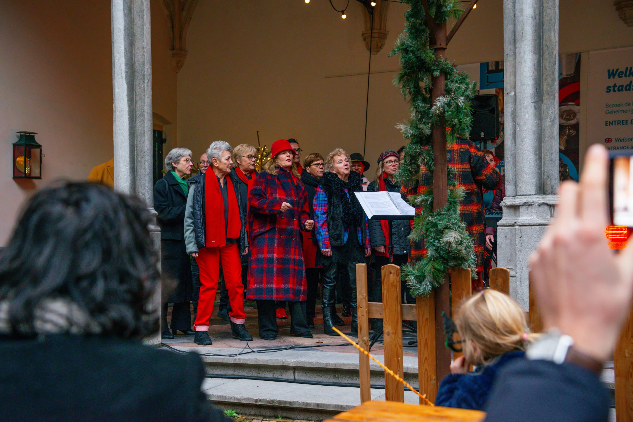 Mensen zingen samen tijdens kerstevenement buiten.