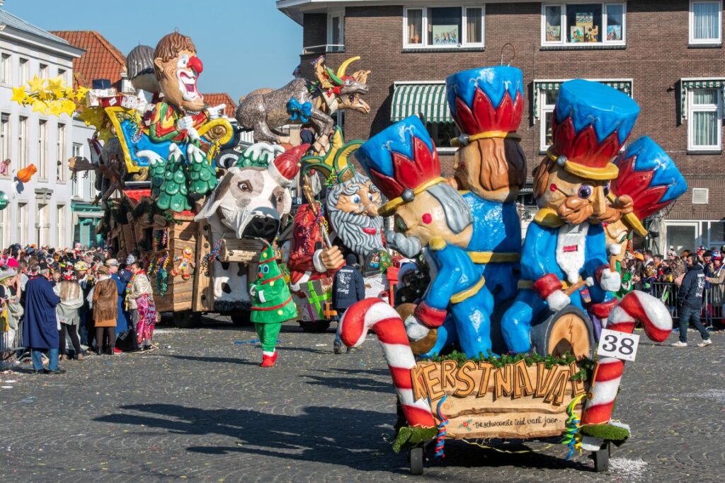 Carnavalsoptocht met kleurrijke praalwagens en menigte.
