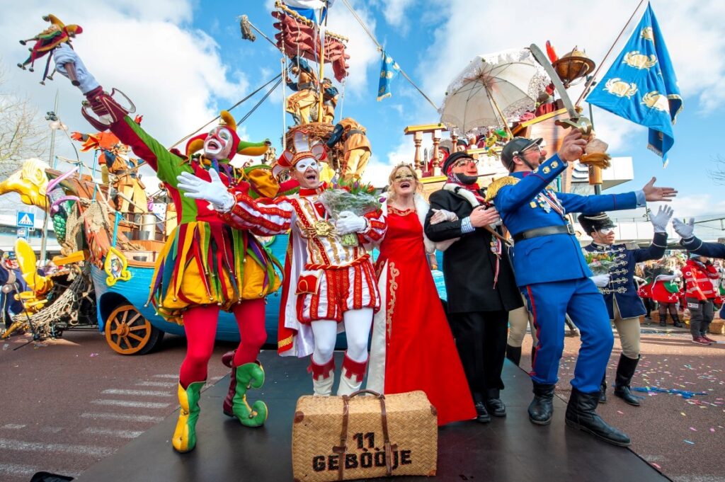 Carnavalsvierders in kleurrijke kostuums tijdens optocht.