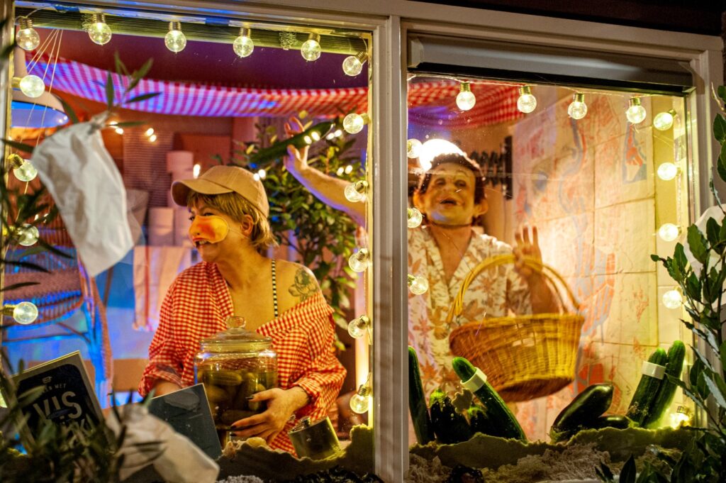 Mensen in kleurrijke etalage met lichtjes en mand.
