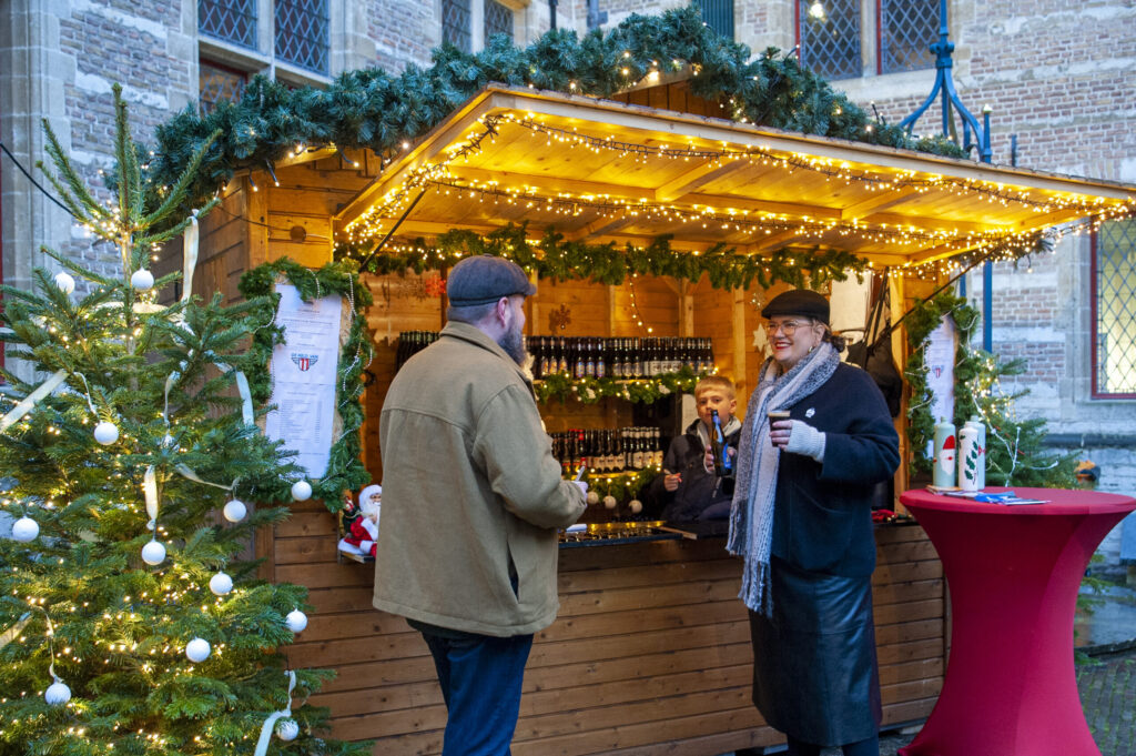 Kerstmarkt kraam met bezoekers genieten warme dranken - Bergen op Zoom