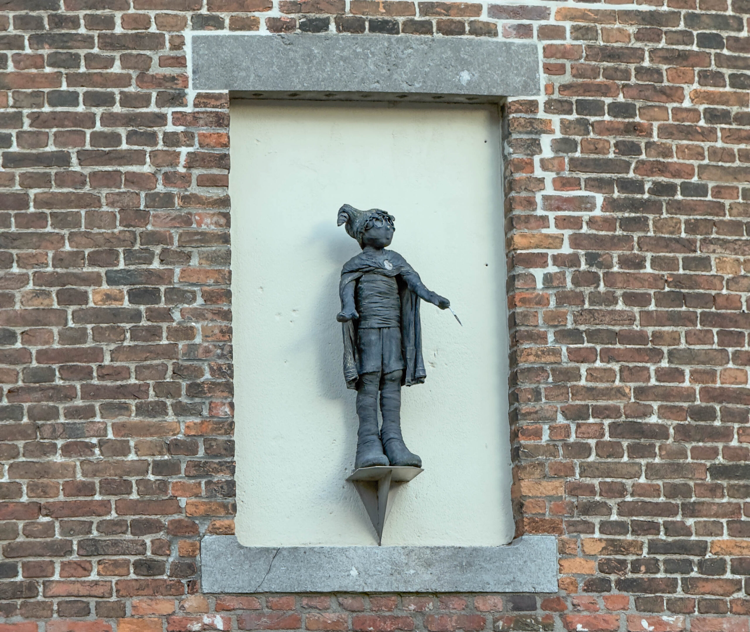 Standbeeld jongen aan bakstenen muur - Bergen op Zoom